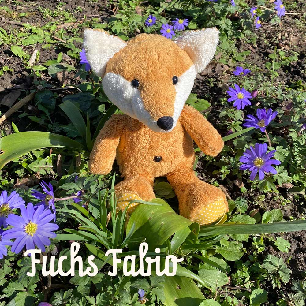 Bio Kuscheltier Fuchs Fabio auf Wiese mit Blümchen sitzend
