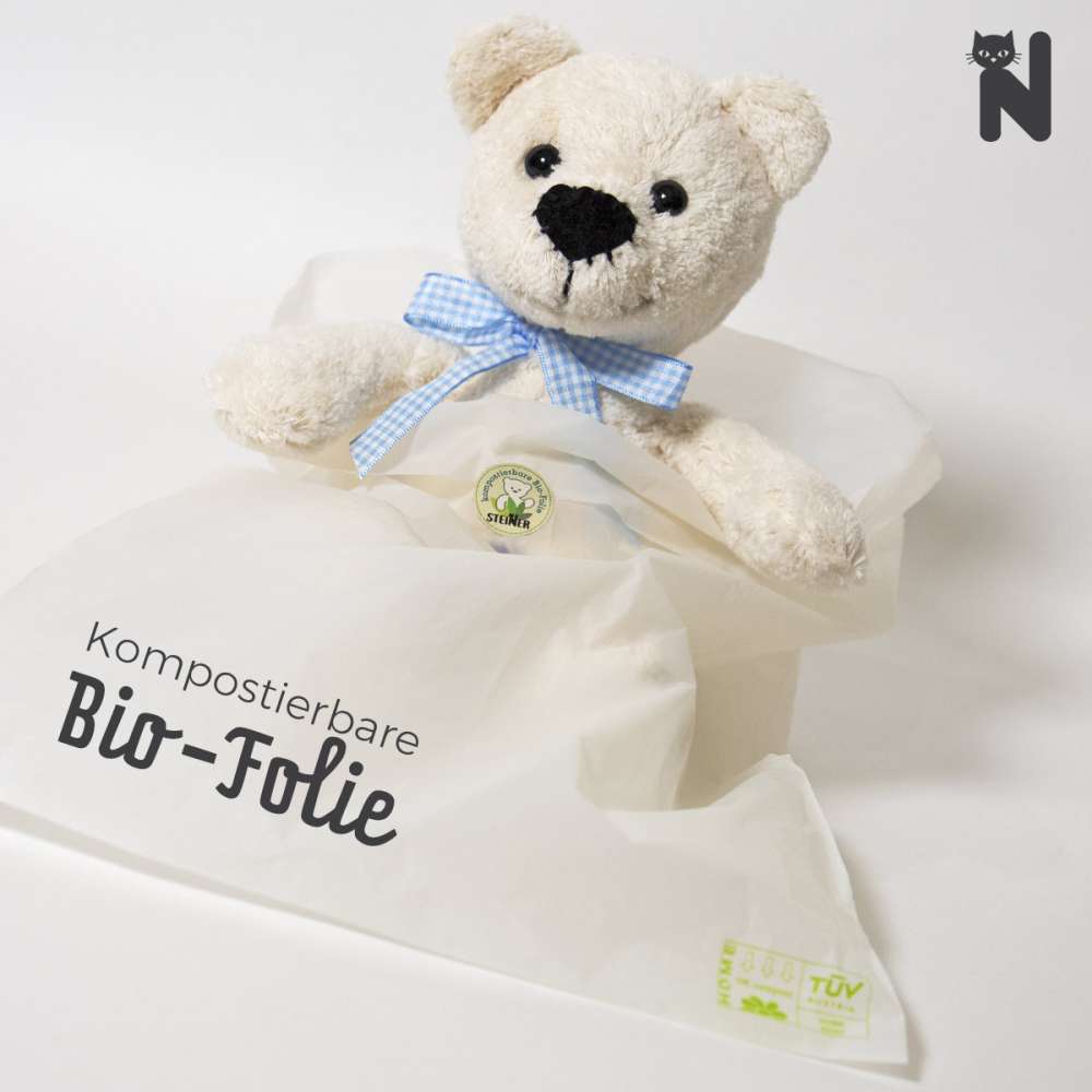 Bio Teddy Bommel von Steiner Kuscheltiere in weiß mit blauem Halsband und in kompostierbarer Bio-Folie