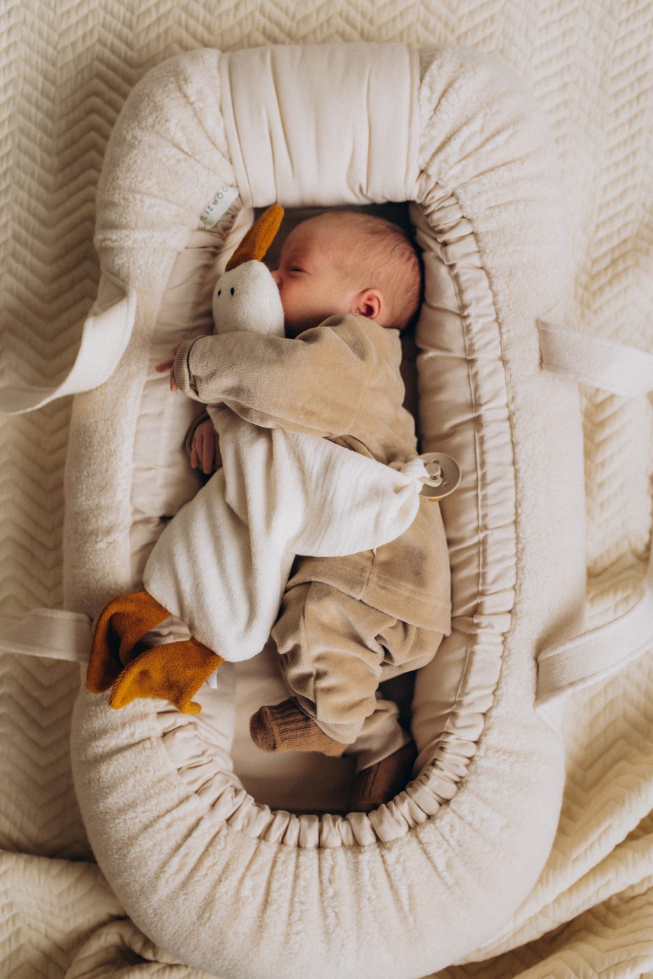 Weiches Wärmekissen mit Kirschkernfüllung in Form einer Gans aus Bio-Baumwolle mit senfgelben Füßen und Schnabel sowie integriertem Beißring für Babys.